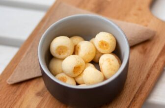 baked breads on round black and white ceramic bowl on the top of brown chopping board Brazilian Cheese Bread