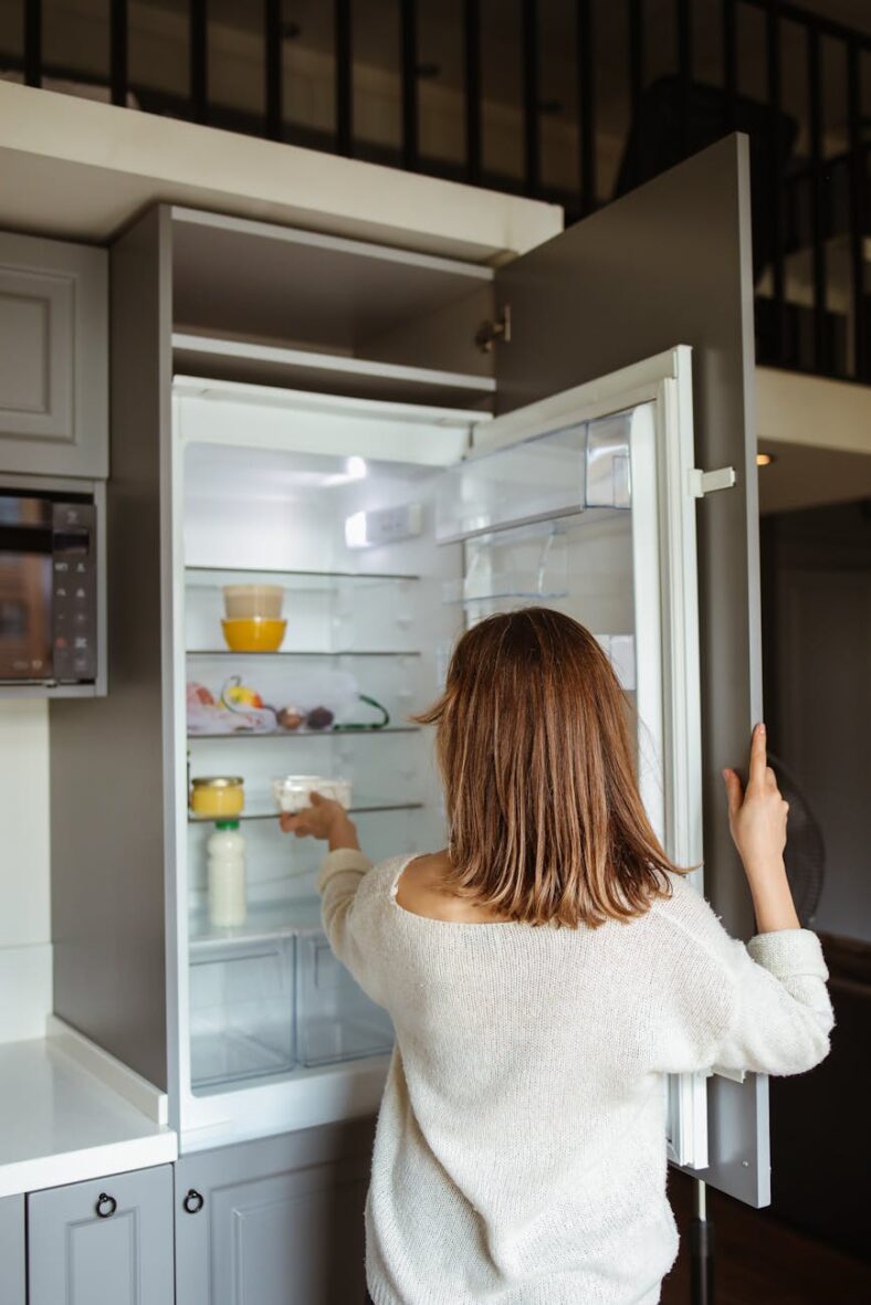 woman in white sweater near refrigerator Guia Geladeira ideal para acertar na escolha