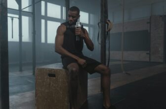 a fit man using a massage gun on his shoulder