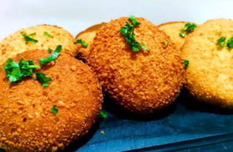 Salgados fritos dourados e crocantes de queijo e presunto empanados com farinha panko, servidos em uma cesta com molhos para acompanhar.