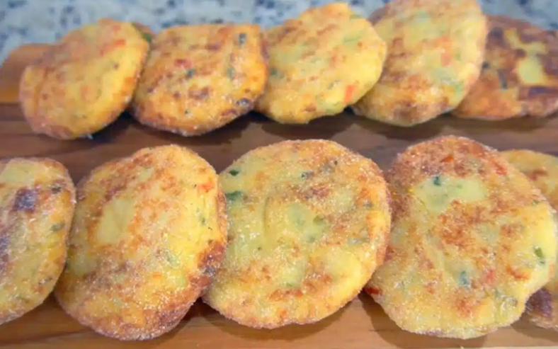 Croquetes de batata com queijo dourados e crocantes, cortados ao meio para mostrar o recheio de muçarela derretida, servidos em prato com molhos.