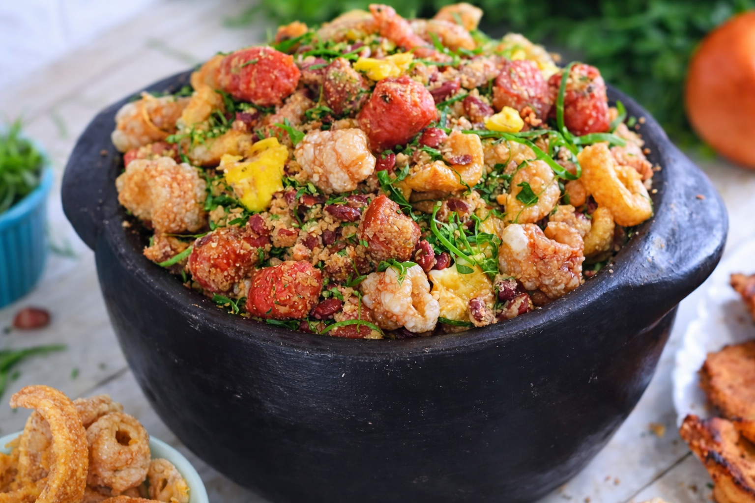 Travessa com feijão tropeiro mineiro, grãos de feijão envoltos em farinha, pedaços de torresmo crocante, linguiças e couve fatiada.